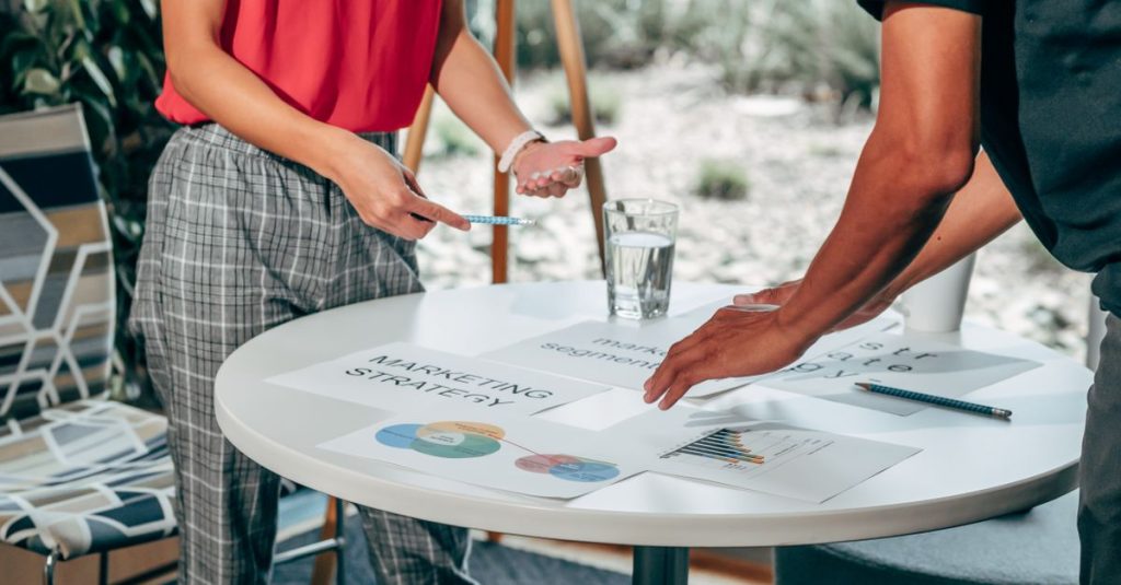 Two people reviewing a marketing strategy document with charts on a table
